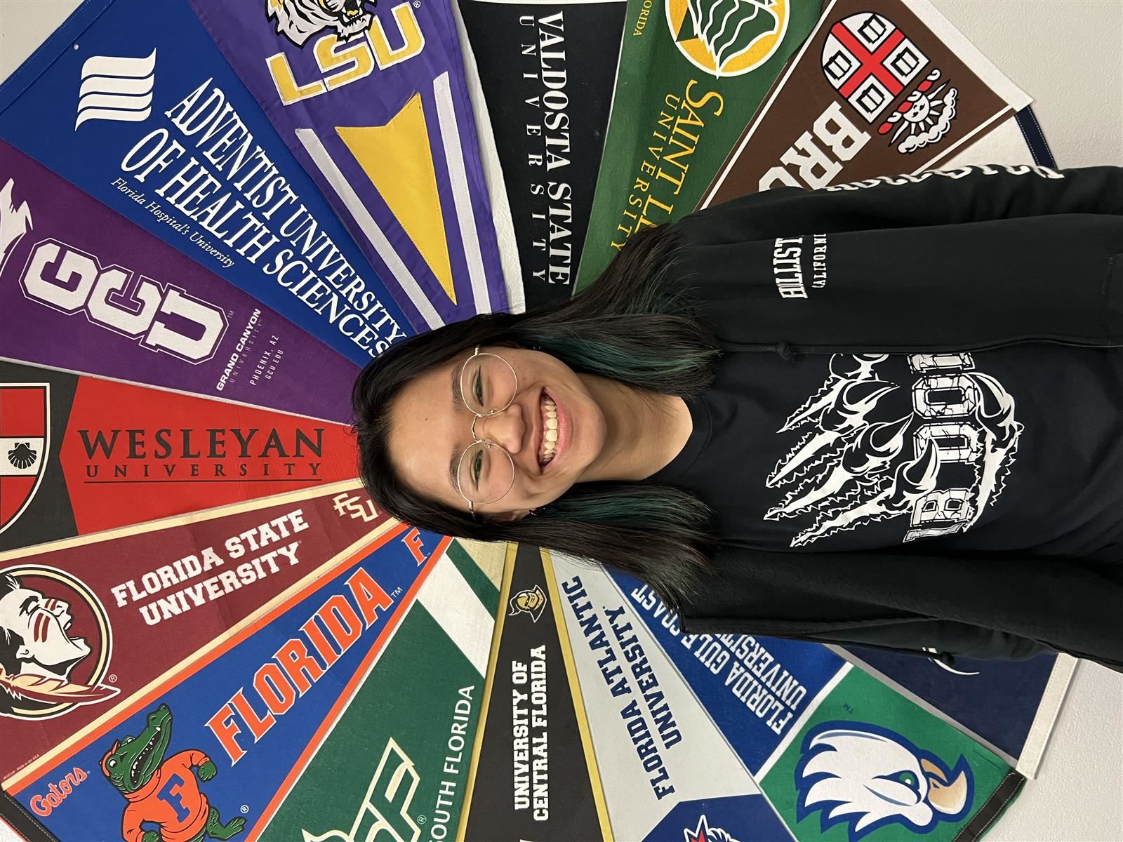 Arden Phann in front of college pennants. 