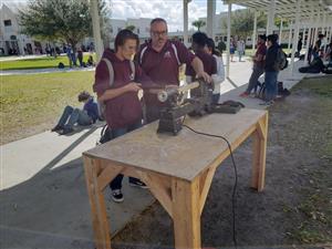 A student and teacher making a bat during carpentry class 