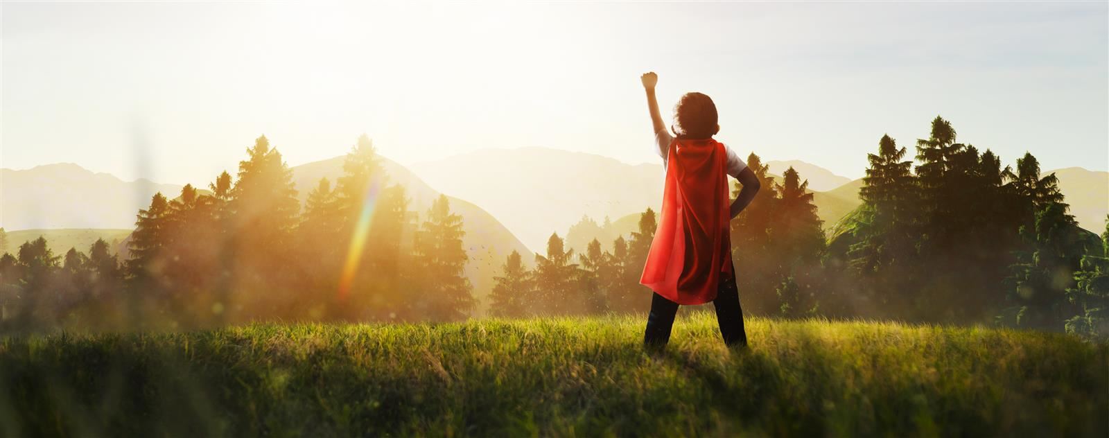 boy wearing cape with fist in air