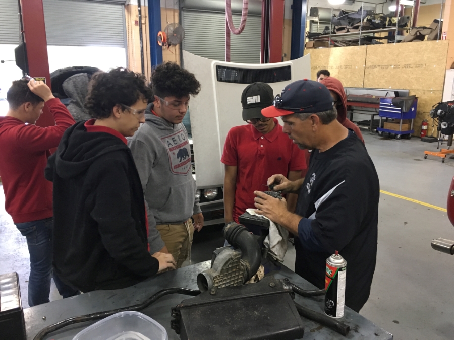 Teacher demonstrating car parts to a group of students.