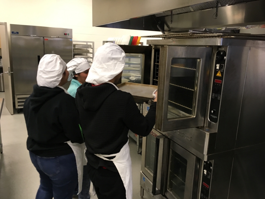 Students taking a pan out of an oven.